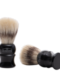 Two Scalpmaster shaving brushes with boar bristles, one standing upright and one lying horizontally, both with black handles and stands.