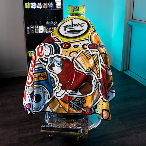 A barber chair draped in a vibrant, graffiti-style printed cape featuring a dog illustration and bold graphic text